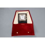 A Cartier stainless steel travelling alarm timepiece, with original fabric pouch