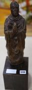 A carving of a saint in prayer, on stand