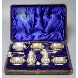 A late Victorian cased silver seven piece condiments set and five spoons (one associated), John