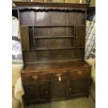 A mid-18th century oak dresser having later boarded plate rack over short drawers and panelled