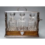 An oak three bottle tantalus, with key, decanters not matching, width 35cmCONDITION: Tantalus