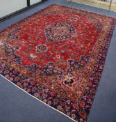 A Mashaed Khorason rug with central medallion and trailing foliate design on a red field, wide