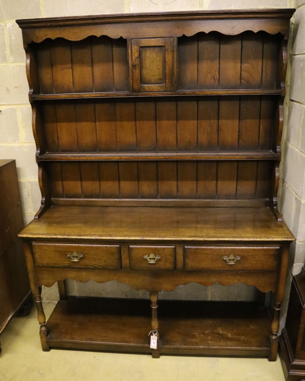 A small Georgian style reproduction oak dresser, having shelved boarded back, shaped apron and pot