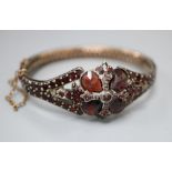 A Victorian gilt white metal and garnet set hinged bangle.