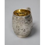 A George III silver barrel shaped christening mug, embossed with figures at play in woodland