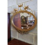 A late Victorian gilt oval wall mirror, surmounted by an urn, flanked by winged griffins, width 70cm