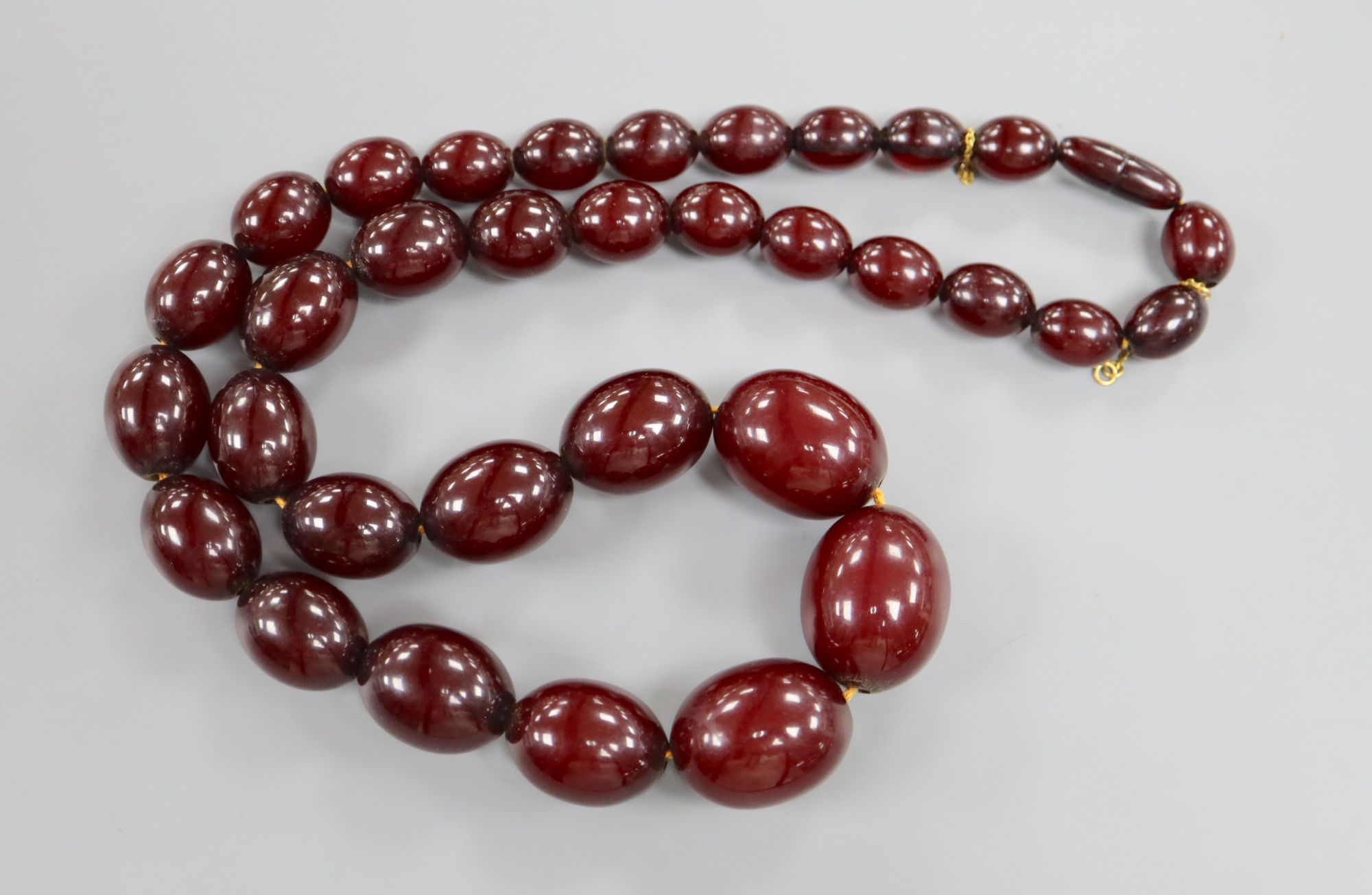 A single strand graduated simulated cherry amber oval bead necklace, 61cm, gross weight 99 grams. - Image 2 of 3
