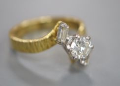 A modern textured 18ct gold and single stone diamond ring, with baguette cut diamond set
