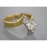 A modern textured 18ct gold and single stone diamond ring, with baguette cut diamond set