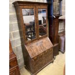 A mid 18th century style walnut bureau bookcase, with two mirrored doors enclosing a single