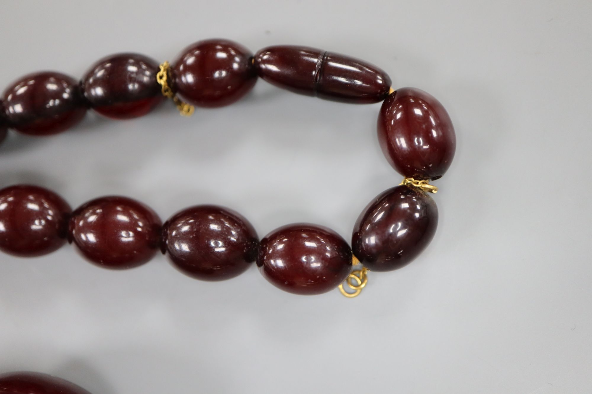 A single strand graduated simulated cherry amber oval bead necklace, 61cm, gross weight 99 grams. - Image 3 of 3