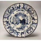 An 18th century Delft blue and white charger centred by a lion, with figural and foliate border,