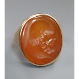 A late 19th century yellow metal and oval carnelian intaglio ring, carved with the head of a