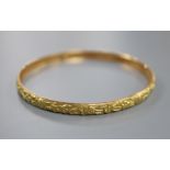 A yellow metal (tests as 18ct) bangle cast with continuous band of flowers, 9g, interior 64mm.