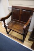 An 18th century oak panel back open armchair with wood seat, raised on turned legs with linking