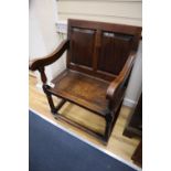 An 18th century oak panel back open armchair with wood seat, raised on turned legs with linking