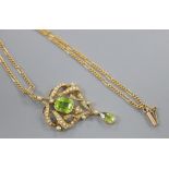 An Edwardian gold, seed pearl and two stone peridot set scroll pendant, overall 53mm, gross 7.4