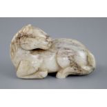 A Chinese white and grey jade figure of a recumbent horse, the stone with some dark brown