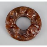A Chinese brown jade bi disc, carved in relief with chilong, 5cm diameter