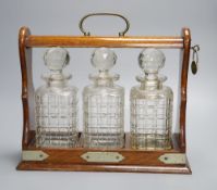 An Edwardian oak cased three decanter tantalus