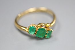 An early 20th century 18ct gold and three stone emerald crossover ring, size Q, gross 2.6 grams.