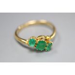An early 20th century 18ct gold and three stone emerald crossover ring, size Q, gross 2.6 grams.