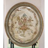 An early 19th century silkwork panel of flowers in a cornucopia, oval 50 x 42cmCONDITION: Embroidery