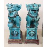 A pair of Chinese turquoised glazed lion dogs, on wood stands, height 58cm overall