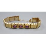 A Victorian engraved yellow metal and three stone garnet set hinged panel bracelet, with safety
