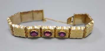 A Victorian engraved yellow metal and three stone garnet set hinged panel bracelet, with safety