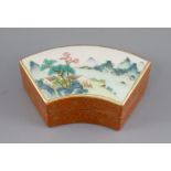 A Chinese coral ground fan-shaped box and cover, bearing a Qianlong mark, the top painted in famille