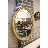 A 19th century oval giltwood mirror with tied-ribbon and floral mounts (faults), 60 x 84cm