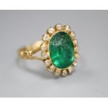 An early 20th century yellow metal, emerald and diamond set oval cluster ring, size M, gross 4 grams