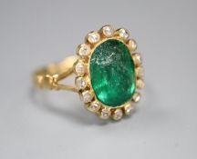 An early 20th century yellow metal, emerald and diamond set oval cluster ring, size M, gross 4 grams