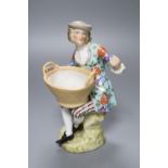 A Sitzendorf porcelain figure of a youth holding a basket, after a Meissen original by J.J.