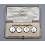A cased set of four early 20th century 9ct, mother of pearl and enamel buttons, in Asprey box.