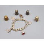 A silver charm bracelet hung with four assorted charms and four thimbles including two silver.