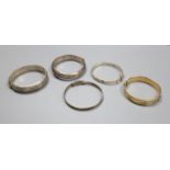 Four assorted silver bangles and a gold plated bangle.