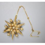 An Edwardian 15ct and graduated split pearl set starburst brooch, 31mm, gross 5.7 grams.