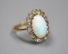 An early to mid 20th century 18ct, white opal and diamond set oval cluster ring, size K, gross 3.1