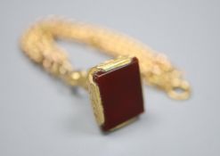 An early 20th century 9ct gold curblink bracelet, hung with a yellow metal overlaid carnelian set