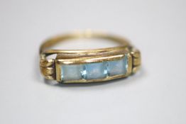 A 333 (8ct) yellow metal and channel set three stone blue topaz? ring, size J, gross 1.4 grams.