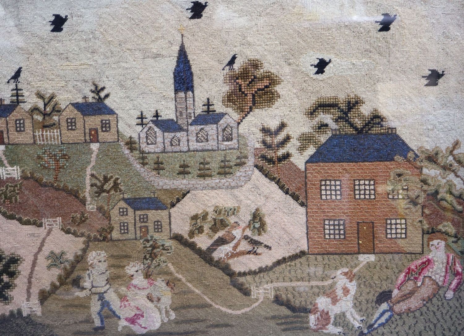 An early 19th century English petit point panel, with father, children and dog in a garden, houses