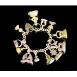 An early 20th century 9ct gold bracelet hung with thirteen assorted gold or gilt metal overlaid