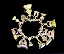 An early 20th century 9ct gold bracelet hung with thirteen assorted gold or gilt metal overlaid