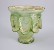 A Roman green glass 'auricular' cup, 2nd/3rd century AD, the funnel shaped body with applied '