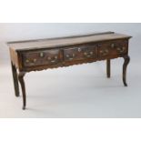 An early 18th century oak dresser base, fitted three long drawers with brass loop handles, on