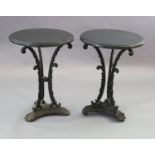 A pair of early Victorian cast iron occasional tables, with later circular black granite tops,