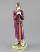 A Russian Gardner porcelain figure of a man holding a staff, mid 19th century, wearing traditional