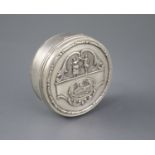 A George V silver circular box and hinged cover, embossed with a ship and dancing figures above,